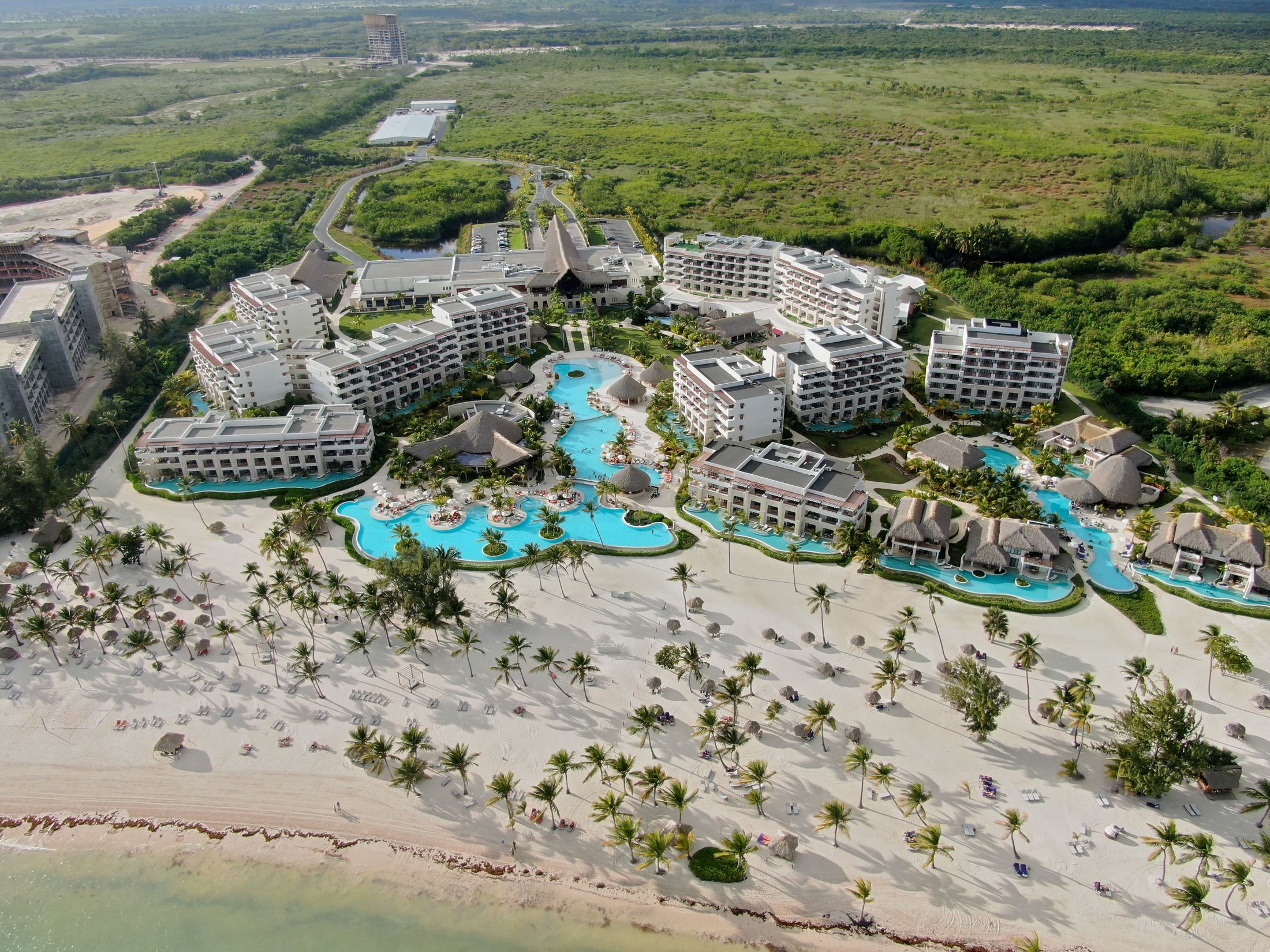 Aerial view of a modern luxury beachfront resort with pools and white sand